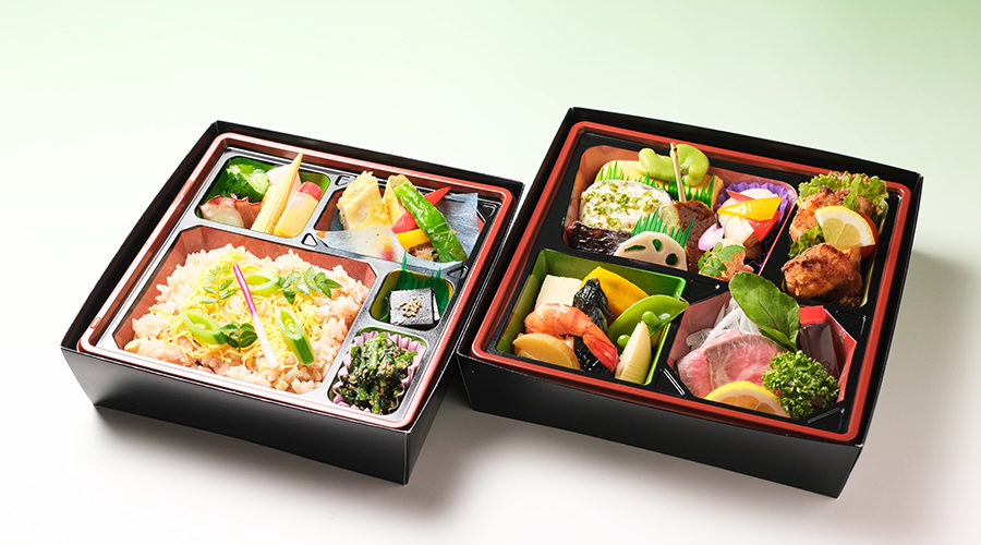 ご飯、海鮮、野菜が色とりどりに盛られた上品な日本料理の弁当が二つ並んでいる様子