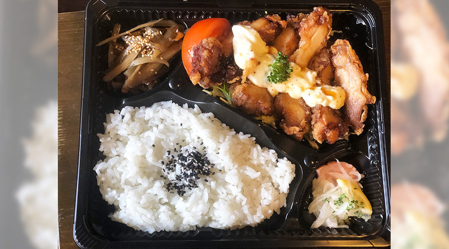 鶏の唐揚げとタルタルソース、白ごまののったご飯、漬物が入った弁当箱の俯瞰
