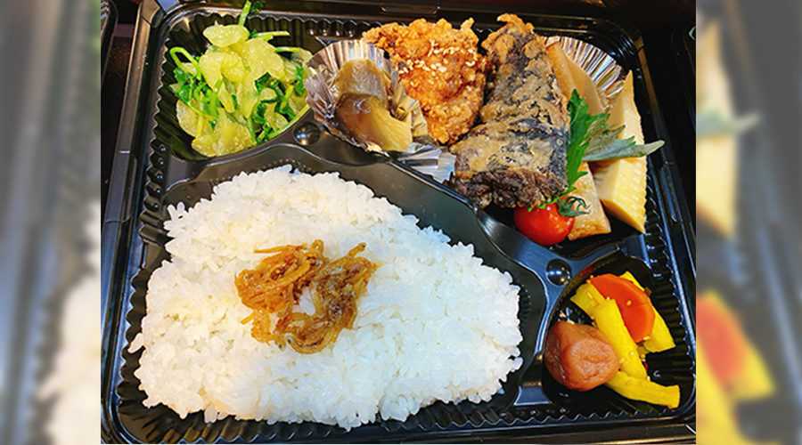 黒いトレイに白ご飯、揚げ物、漬物、副菜がバランスよく並んだ弁当